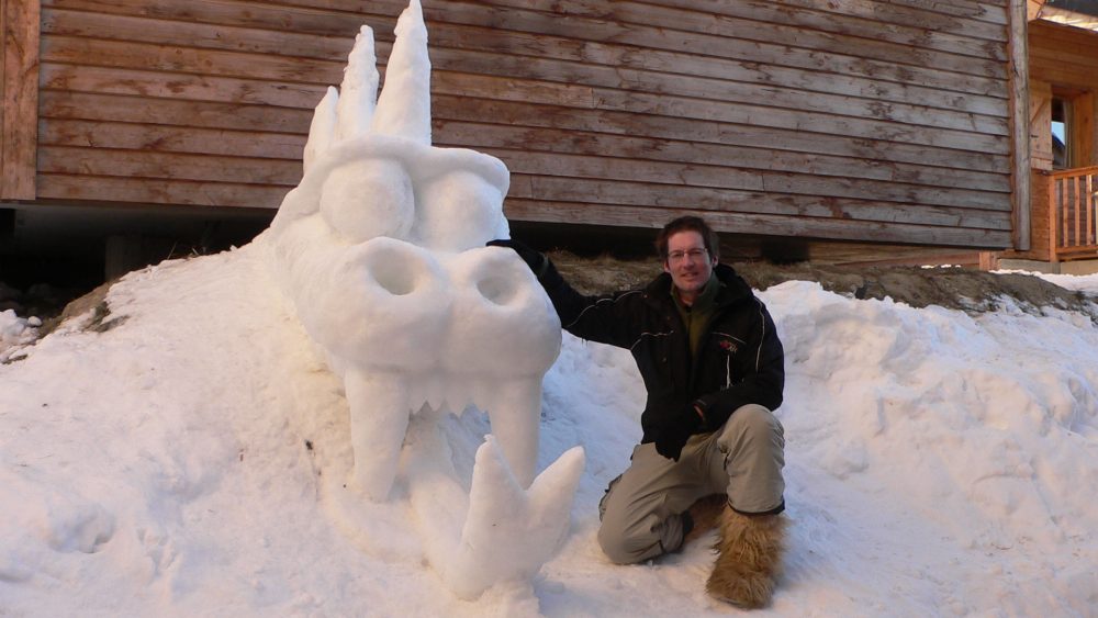 Marcel met een sneeuwkunstwerk in de vorm van een grote drakenkop